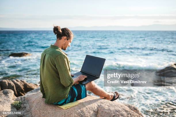 joven nómada digital trabajando junto al mar - expatriado fotografías e imágenes de stock