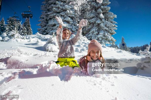 ragazzo e sua sorella che si divertono sulla neve durante il giorno d'inverno su una montagna - vacanza sulla neve foto e immagini stock
