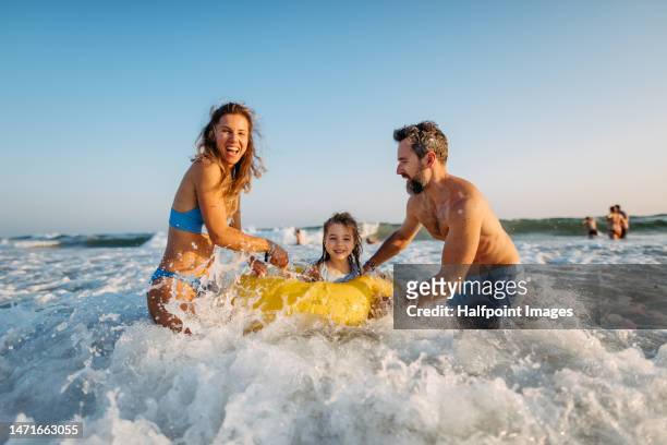 young family enjoying time at sea. - family on beach stock-fotos und bilder