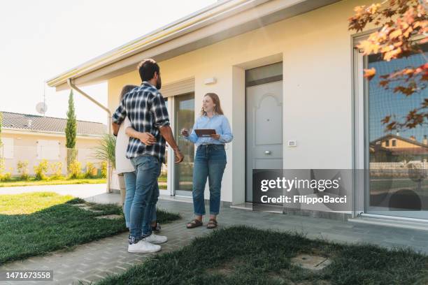 a real estate agent is showing an house to a couple - new home exterior stock pictures, royalty-free photos & images