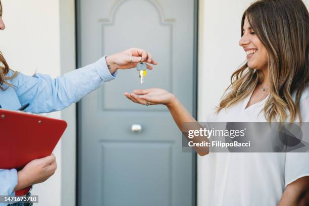 a real estate agent is giving the house keys to her customer - agent and handing keys stockfoto's en -beelden