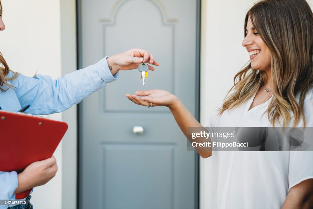 A real estate agent is giving the house keys to her customer