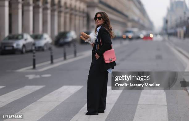 Füsun Lindner seen wearing Celine black sunglasses, COS light blue striped button shirt, COS black blazer jacket, COS matching black wide leg suit...