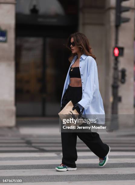 Füsun Lindner seen wearing Celine black sunglasses, COS light blue striped button shirt, COS black wide leg suit pants, Dior black short tube top...