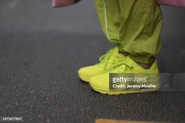Palina Kozyrava seen wearing Revolve neon green nylon pants, Mango pink long wool coat, Sketchers neon green / yellow leather sneakers, during Paris...