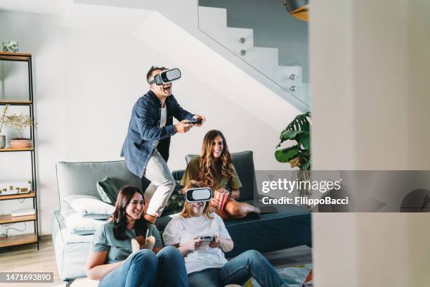 four friends are playing video games together at home - globe party stock pictures, royalty-free photos & images