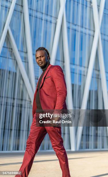 young adult businessman walking in city downtown - roter anzug stock-fotos und bilder