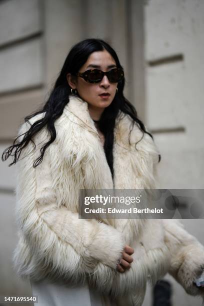 Guest wears black and brown sunglasses, a black pullover, a white latte fur coat, earrings, outside Lanvin, during Paris Fashion Week - Womenswear...