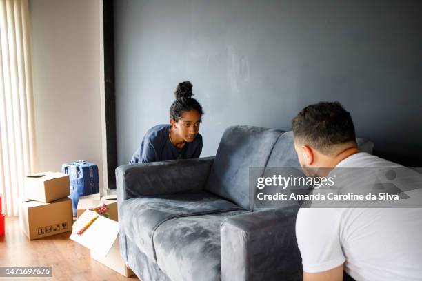 young woman helps her father to move sofa on moving day - familie sofa stock pictures, royalty-free photos & images