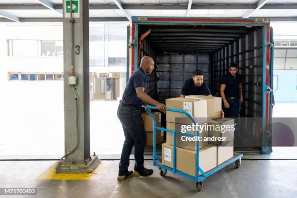 group of workers loading merchandise on a truck at a distribution warehouse - container unloading stock pictures, royalty-free photos & images