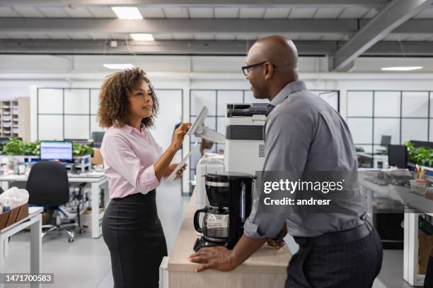 business woman using a copying machine at the office and talking to a coworker - computer printer stock pictures, royalty-free photos & images