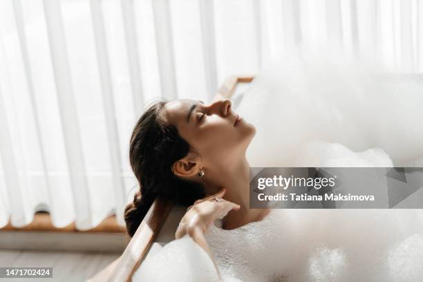 young woman relaxing in bath tub full of foam bubbles. self care and mental health concept. - beautiful woman bath photos et images de collection