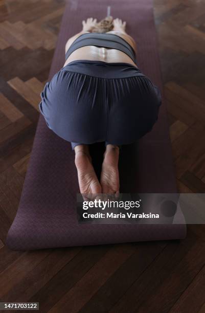 high angle view of woman practicing yoga in half-tortoise or child pose - yoga pants bent over stock pictures, royalty-free photos & images
