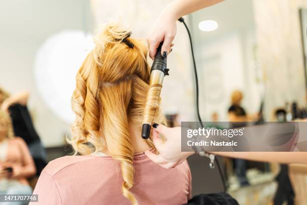 woman on hairdresser making locks with curling iron - hair curlers stock pictures, royalty-free photos & images