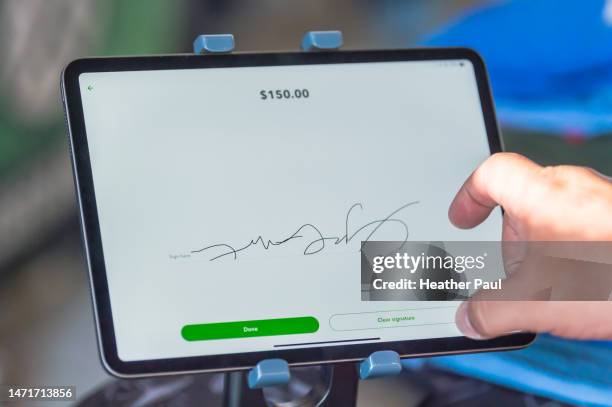 person signing their name on a digital tablet to pay for a credit card charged item - digital signature stock-fotos und bilder