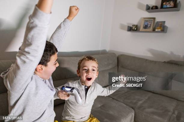 Brothers Celebrating Win At The Video Games While Playing Playstation Together High-Res Stock Photo