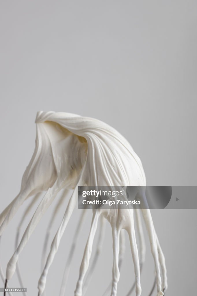 Whipped ganache or cream with vanilla seeds on whisk.