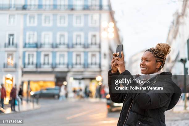 afro woman taking photo with smartphone on the street - lisbon tourist stock pictures, royalty-free photos & images