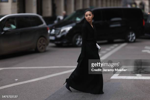 Yuwei Zhangzou seen wearing a black long dress, a white clutch and black boots before the Balenciaga show on March 05, 2023 in Paris, France.