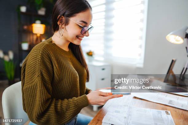 young woman paying financial bills using qr code scanner on mobile banking app - pay day stock pictures, royalty-free photos & images