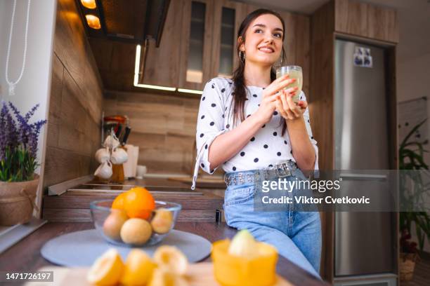 lovely young woman enjoying a glass of freshly made lemonade in the kitchen - drinking lemonade stock pictures, royalty-free photos & images