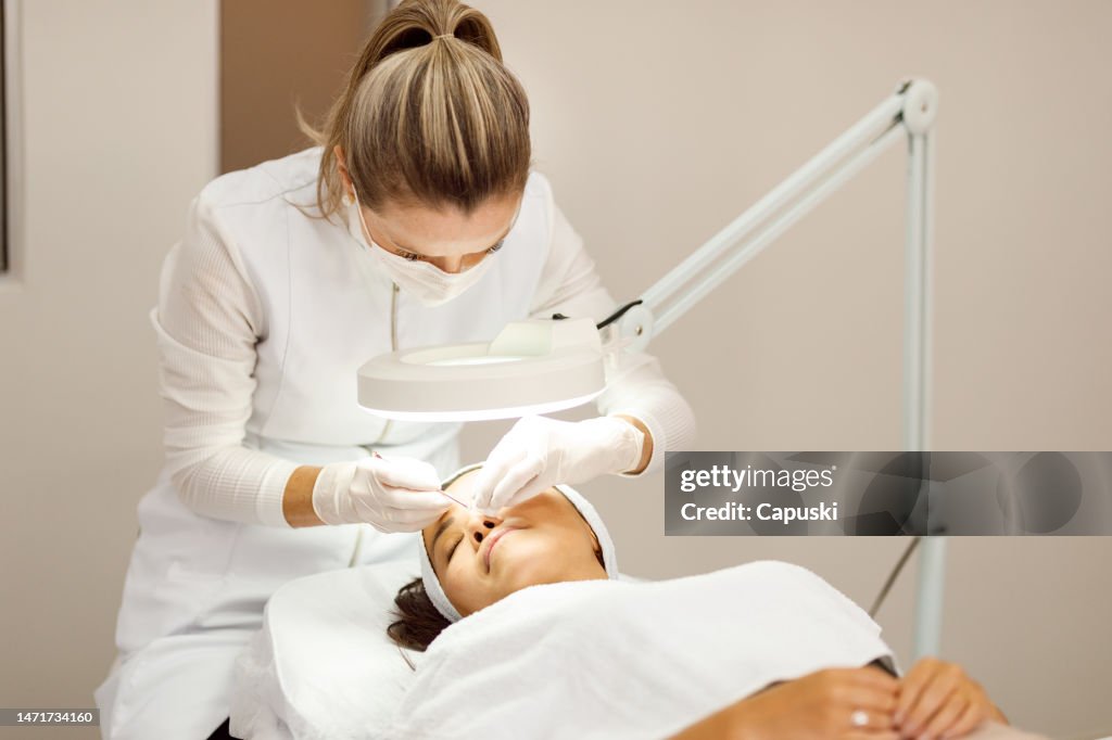 Beautician extracting pimples from a woman's face