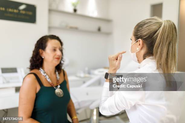 dermatologist showing places of procedures to pacient - dermatologists talking to each other patient stock pictures, royalty-free photos & images