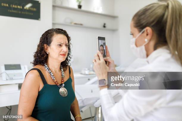 dermatologist taking before and after pictures of a curly haired woman - dermatologists talking to each other patient stock pictures, royalty-free photos & images