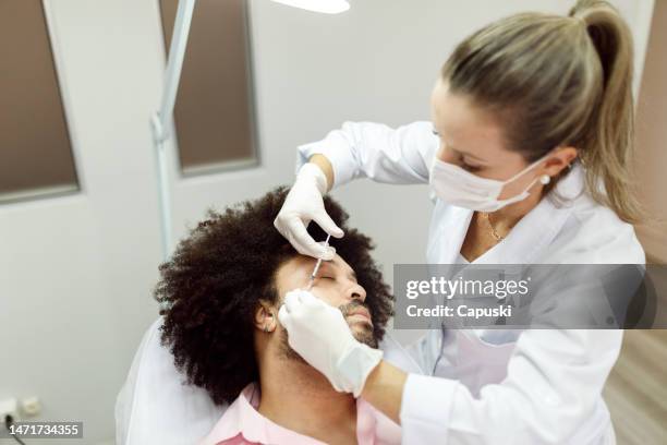 man getting botox applied to his cheek - botox injections stock pictures, royalty-free photos & images