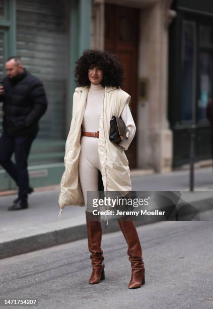 Fashion Week Guest is seen wearing a full beige outfit, beige vest, beige pullover, beige leggings and brown leather boots, Louis Vuitton handbag...