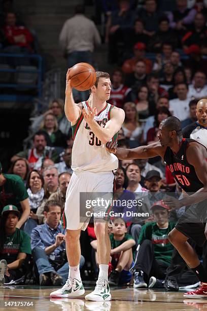 Jon Leuer of the Milwaukee Bucks looks to pass the ball over Solomon Alabi of the Toronto Raptors on April 23, 2012 at the Bradley Center in...