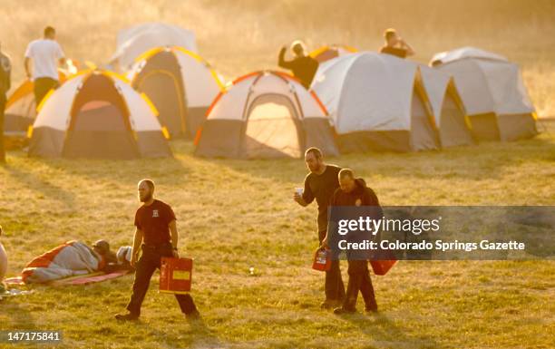 Firefighters stir from their tents at a firefighter camp at Holmes Middle School early Tuesday morning, June 26 to begin work on the fourth day of...