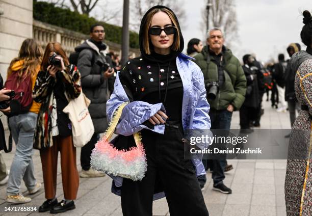 Katya Bychkova is seen wearing a light blue jacket, black hoodie, black pants and faux fur bag with black sunglasses outside the Louis Vuitton show...