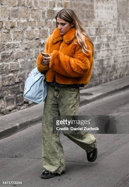 Guest is seen wearing a faux fur orange jacket, denim jeans and light blue bag outside the Rokh show during Paris Fashion Week F/W 2023 on March 06,...