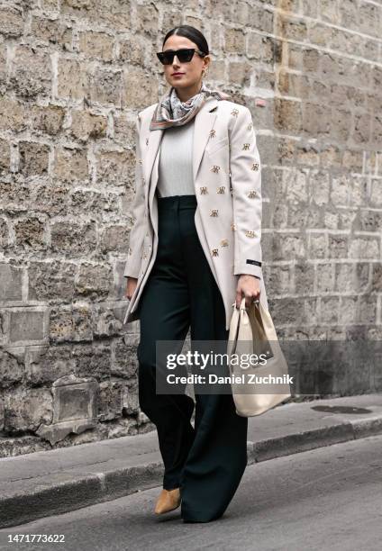 Julia Haghjoo is seen wearing a white and gold coat, green pants, cream bag and scarf outside the Rokh show during Paris Fashion Week F/W 2023 on...