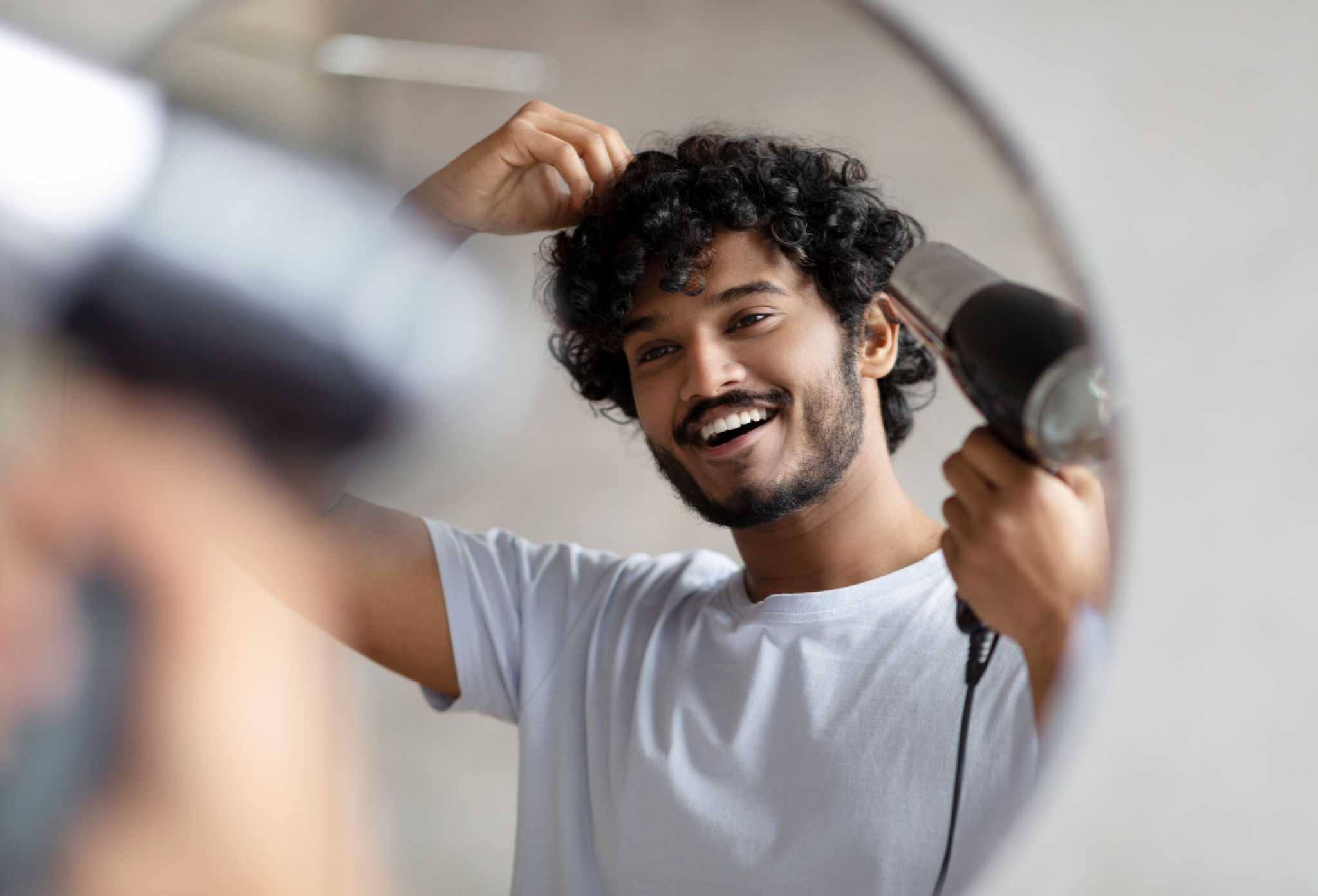 Homem indiano animado usando secador de cabelo após o banho, secando o cabelo encaracolado, fazendo penteado, fazendo rotina matinal Homem indiano animado usando secador de cabelo após o banho, secando o cabelo encaracolado, fazendo penteado, fazendo rotina matinal