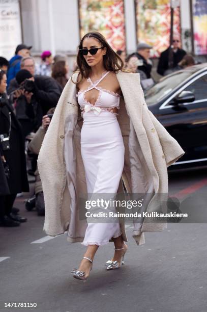 Tamara Kalinic seen wearing a total Giambattista Valli look with a white dress, silver high heels, a white bag, a beige coat and black shades outside...