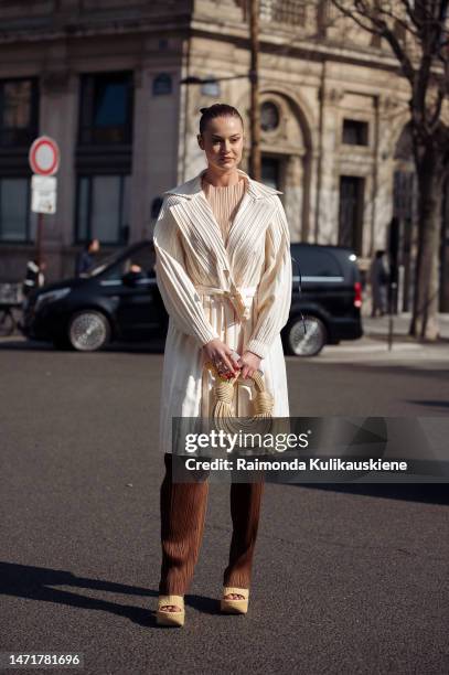 Guest is seen wearing brown wide pants, beige shoes, beige coat and beige bag outside the Issey Miyake show during Paris Fashion Week - Womenswear...