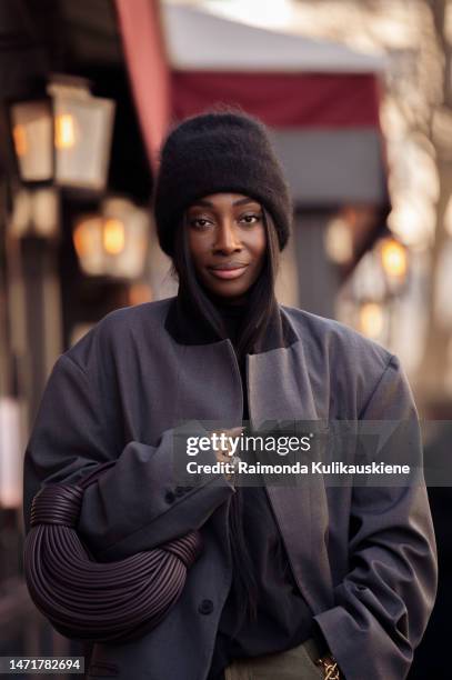 Guest is seen wearing army green cargo pants, black top, grey oversized blazer, dark brown bag and black wool hat outside the Issey Miyake show...