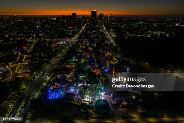 aerial view city of adelaide eastside at dusk with illuminated fringe festival activities in the public parklands in kaurna country - adelaide people stock pictures, royalty-free photos & images