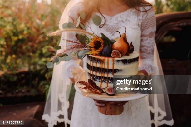 bride holding wedding cake - boho wedding dresses stock pictures, royalty-free photos & images