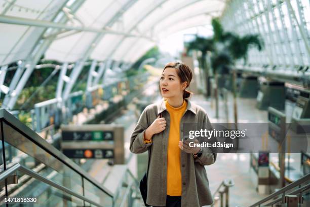 young asian businesswoman using smartphone while walking up the stairs at subway station. commuting to work. travelling on public transportation in the city. technology in everyday life. business on the go - day in the life stock pictures, royalty-free photos & images