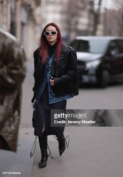 Fashion Week Guest is seen wearing a black turtleneck, blue denim jeans jacket, black leather jacket, black skirt and black leather heels and silver...