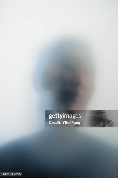 woman moody portrait behind translucent glass - frosted glass stockfoto's en -beelden