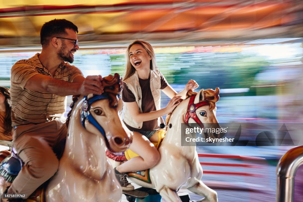 Carefree couple on merry-go-round carousel ride in blurred motion.