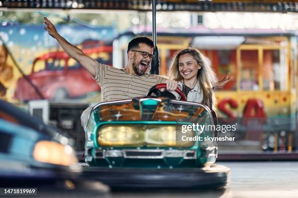 glückliches paar mit spaß beim fahren stoßstange auto im vergnügungspark. - autoscooter stock-fotos und bilder