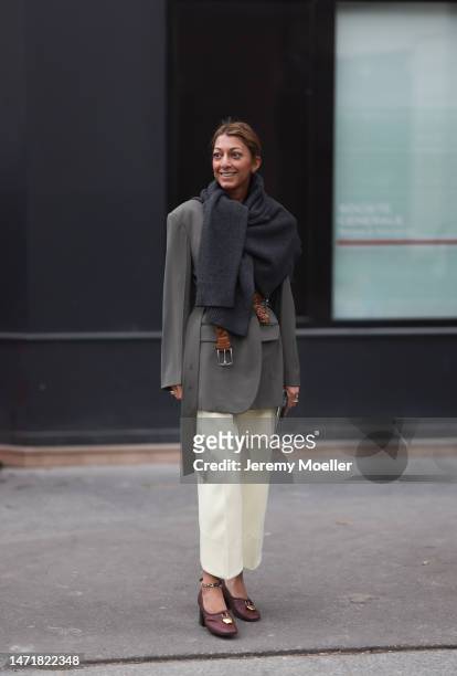 Fashion Week Guest is seen wearing a khaki blazer, grey scarf and brown belt and wide beige pants and brown leather heels outside Lanvin show during...