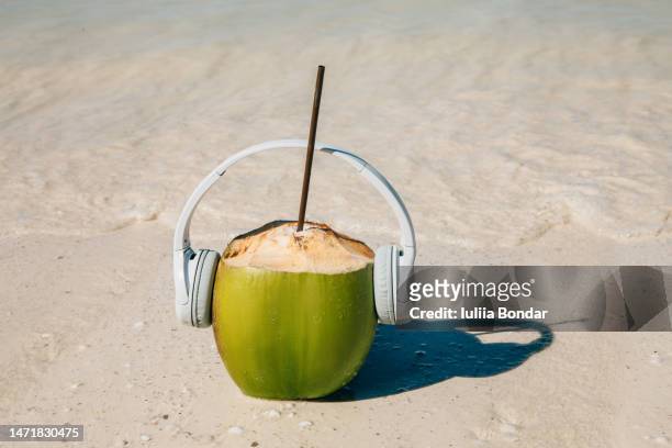 coconut with headphones on a beach - coconut white background stockfoto's en -beelden