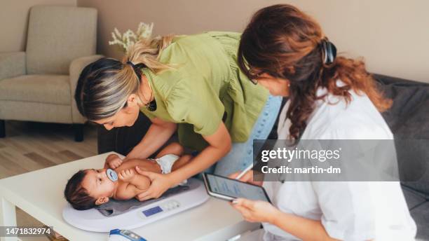 médico visitando a la madre joven en casa para el chequeo de rutina del recién nacido - comadrona fotografías e imágenes de stock