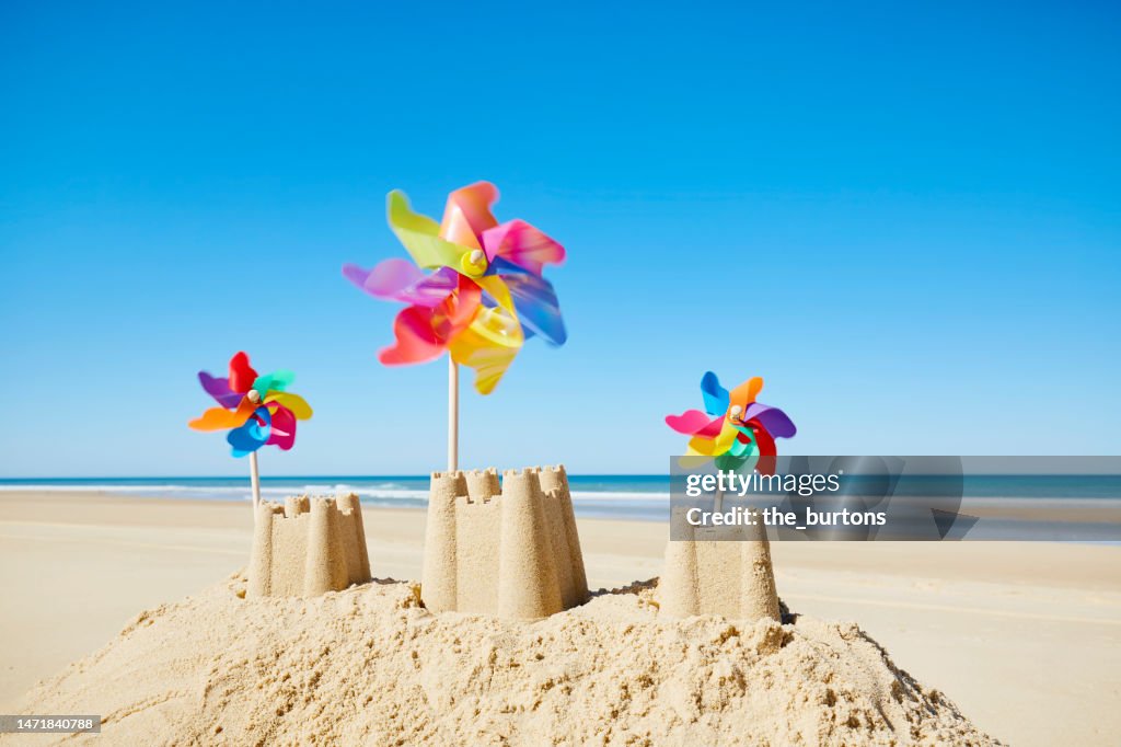 Sandcastle with colorful pinwheels on the beach against sea and blue sky